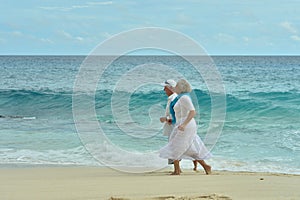Portrait of happy elderly couple running on tropical beach