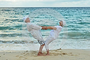 Portrait of happy elderly couple on tropical beach exercising