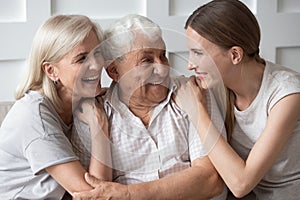 Portrait of happy elderly parents and adult daughter hugging photo