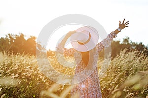 Portrait of happy and enjoying young woman on a meadow on a sunny summer day. Cheerful girl on sunset. Lifestyle and happiness