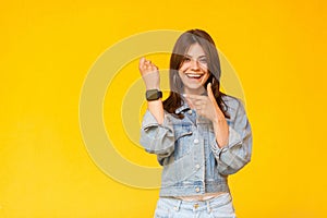 Portrait of happy excited beautiful brunette young woman with makeup in denim casual style standing, looking at camera, pointing