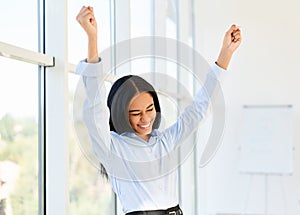 Portrait of happy excited black businesswoman with arms raised celebrating success