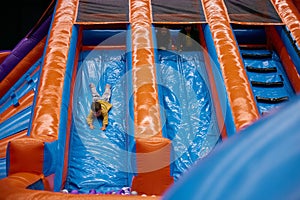 Portrait of happy excited child riding down on inflatable slide