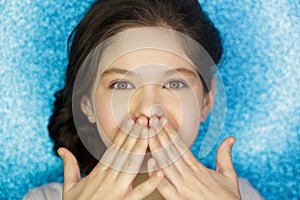 Portrait of a happy excited girl open mouth keeping hands at her face isolated over blue background