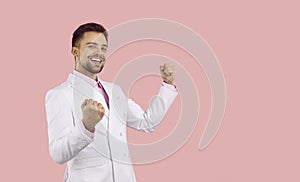 Portrait of happy excited handsome young man in white suit celebrating his success