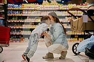 Portrait of happy excited pregnant mom and son fooling around in store