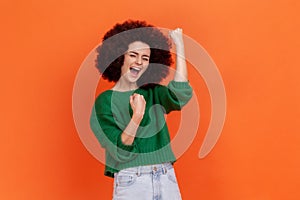 Portrait of happy excited woman with Afro hairstyle wearing green casual style sweater celebrating