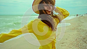 portrait happy expression woman with blowing hair wearing yellow shirt having fun on beach and joyfully running