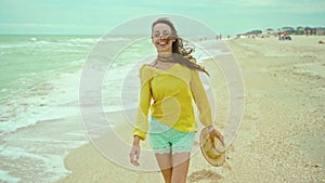 portrait happy expression woman with blowing hair wearing yellow shirt having fun on beach and joyfully running