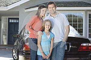 Retrato familia feliz contra auto a casa 
