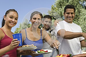 Portrait Of Happy Family Around The Grill At Picnic