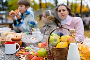 Portrait of a happy family in autumn city park. People are sitting at the table, eating and talking. Posing against the background