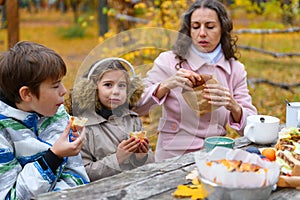 Portrait of a happy family in autumn city park. People are sitting at the table, eating and talking. Posing against the background