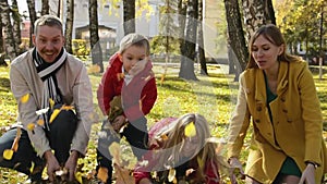 Portrait of a happy family in an autumn park. Parents and children throw orange leaves in the air