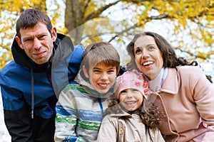 Portrait of a happy family in an autumn park. People pose against the background of beautiful yellow trees. They hug and are happy