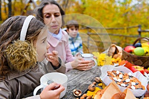 Portrait of a happy family in an autumn park. People are sitting at the table, eating and talking. Posing against the background