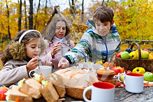 Portrait of a happy family in an autumn park. People are sitting at the table, eating and talking. Posing against the background