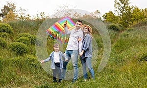 Portrait of happy family with bright kite in countryside