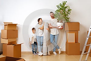 Portrait of happy family with cardboard boxes in new house at moving day