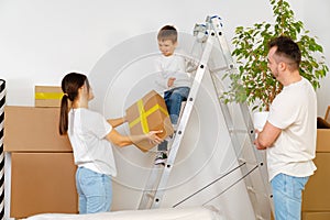 Portrait of happy family with cardboard boxes in new house at moving day