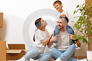 Portrait of happy family with cardboard boxes in new house at moving day