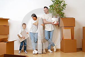 Portrait of happy family with cardboard boxes in new house at moving day