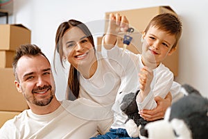 Portrait of happy family with cardboard boxes in new house at moving day