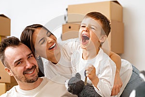 Portrait of happy family with cardboard boxes in new house at moving day