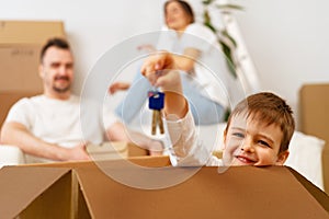 Portrait of happy family with cardboard boxes in new house at moving day