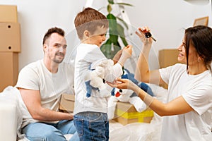 Portrait of happy family with cardboard boxes in new house at moving day