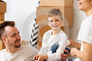 Portrait of happy family with cardboard boxes in new house at moving day