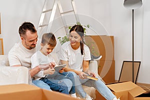 Portrait of happy family with cardboard boxes in new house at moving day