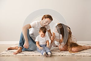Portrait of happy family on carpet near white wall