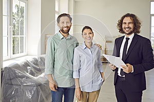 Portrait of happy family couple together with estate agent in new house or apartment