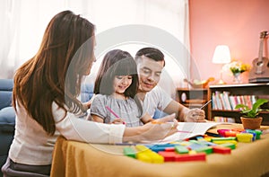 Portrait of happy family daughter girl is learning drawing book together with parent