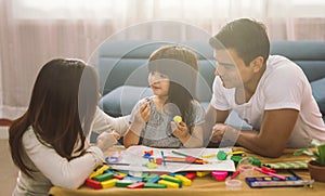 Portrait of happy family daughter girl is learning to use colorful play dough together with parent.