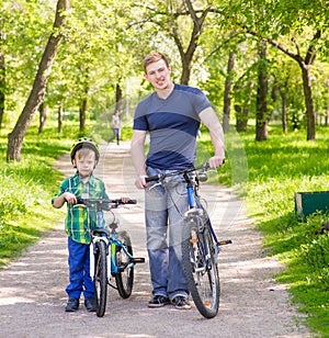 Portrait of a happy family - father and son bicycling in the park