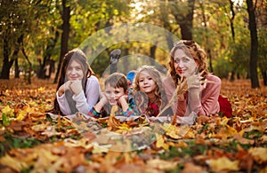 Portrait of happy family in forest park in autumn colorful landscape, motherhood and carefree childhood in nature outdoors