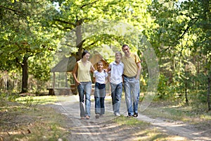 Portrait of happy family of four in autumn park walking