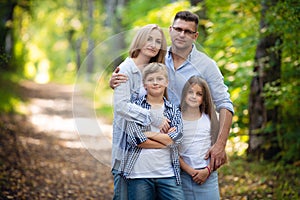 Portrait of happy family of four in a green summer park