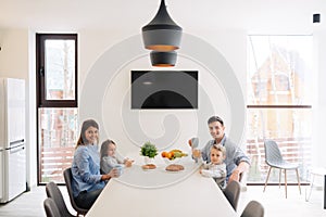 Portrait of happy family having breakfast together at home on modern and stylish kitchen