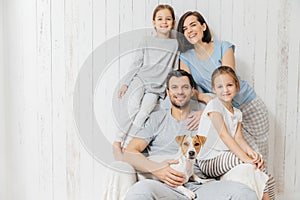 Portrait of happy family indoor. Handsome father holds dog, beau