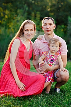 Portrait of happy family with little daughter in park