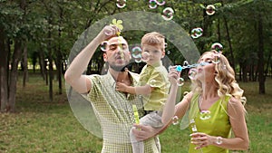 Portrait of a happy family with a little son in a Park with soap bubbles.