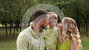 Portrait of a happy family with a little son in the Park in summer. Slow motion.