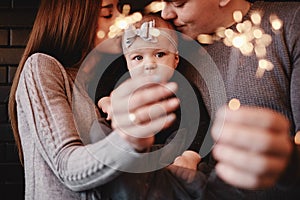 Portrait of happy family, mom, dad and baby girl with sparklers and light. family in anticipation of Christmas. selective photo