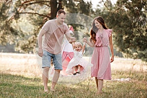 Portrait of happy family. Mom, dad and daughter walk in the park in nature. Young family spending time together on