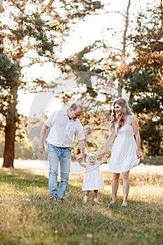 Portrait of happy family. Mom, dad and daughter walk in the park in nature. Young family spending time together on vacation,