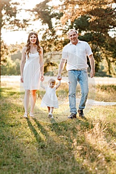 Portrait of happy family. Mom, dad and daughter walk in the park in nature. Young family spending time together on vacation,