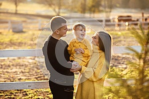 Portrait of happy family. Mom, dad hugging daughter in autumn park. Young couple spending time together on vacation, outdoors. The